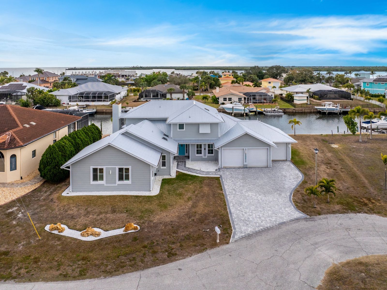 Aerial view of 139 SW Seville Place showing the home, paver driveway, pool cage and canal frontage